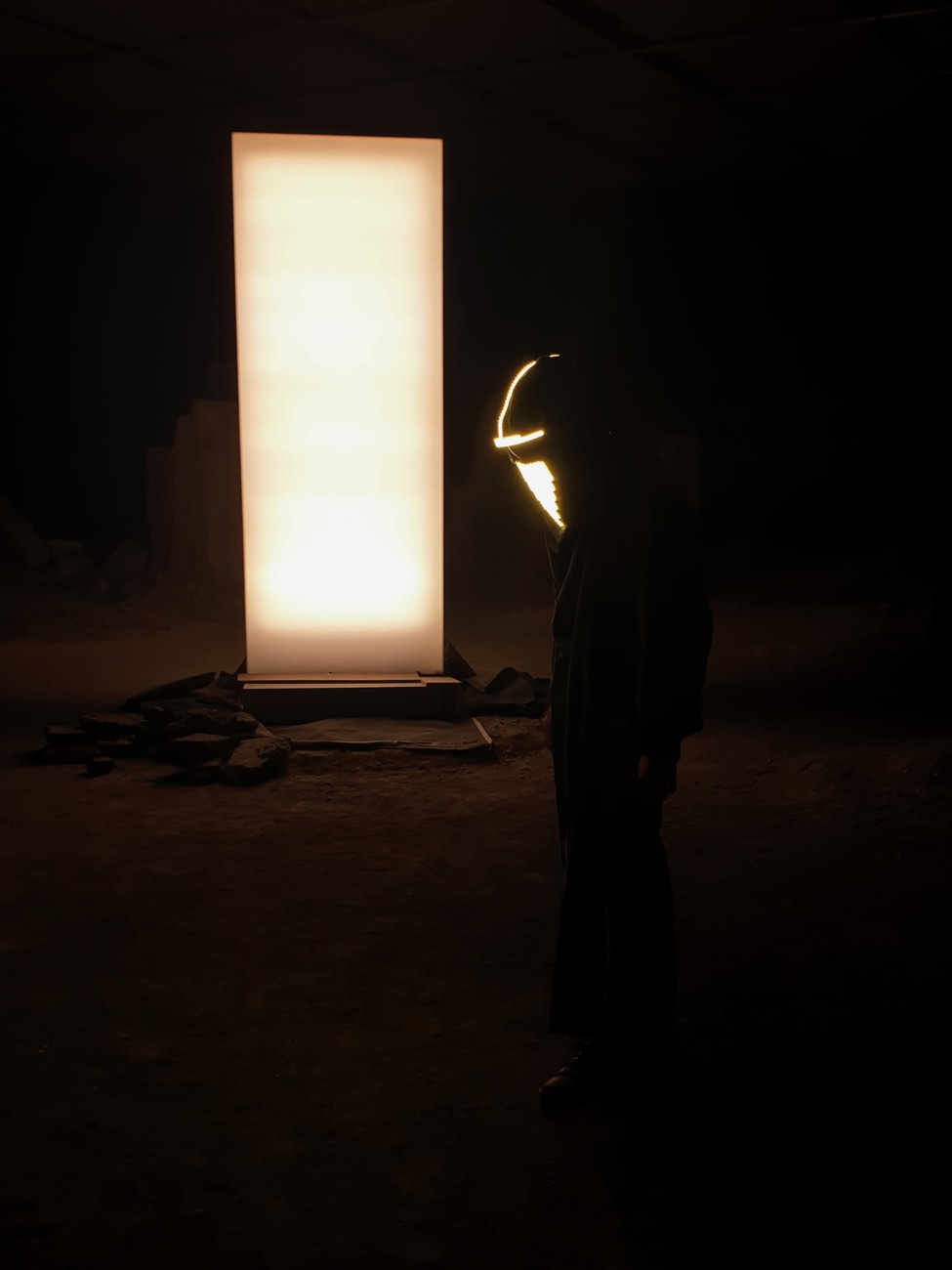 Solastalgia — silhouette au masque lumineux devant le monolithe